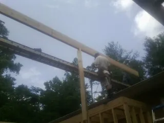 Carpenter setting a ridge beam over a new addition frame — Ice Dam Removal by Roofing Brothers in Mc Coll