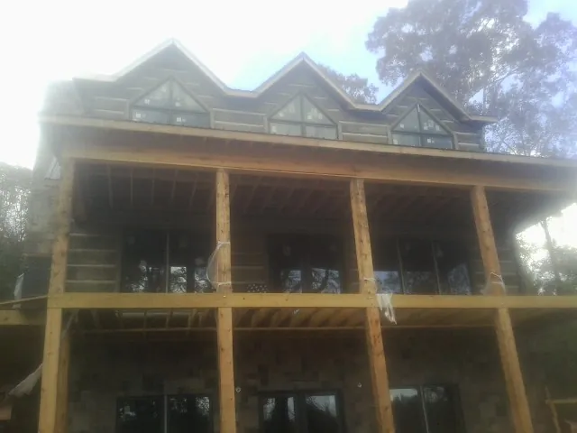 Dormers and porch framing on a large log home under construction — Roof Coating work by our crew in Mc Coll