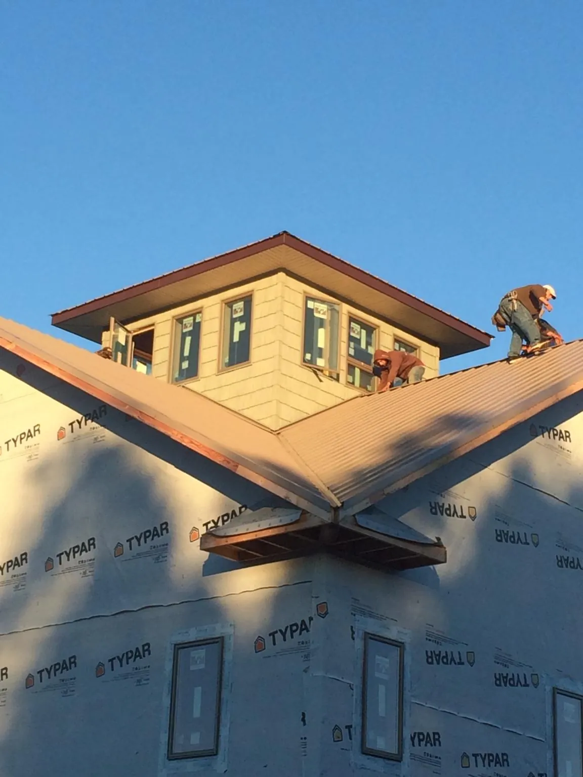 Roofers working around a rooftop cupola on a new metal roof at sunset — Roof Waterproofing in Mc Coll by Roofing Brothers